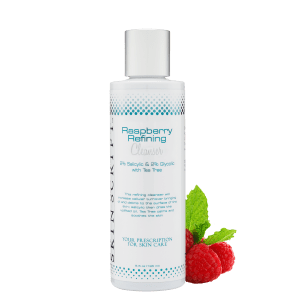 A bottle of raspberry refining lotion next to raspberries.