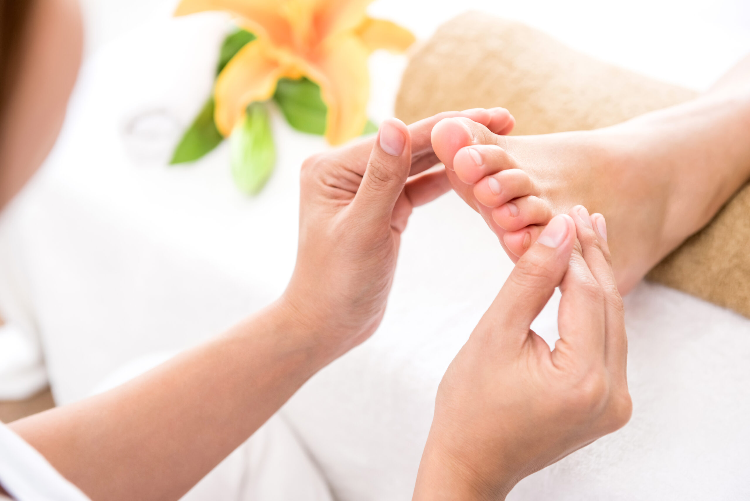 Professional therapist giving relaxing reflexology foot massage to a woman in spa